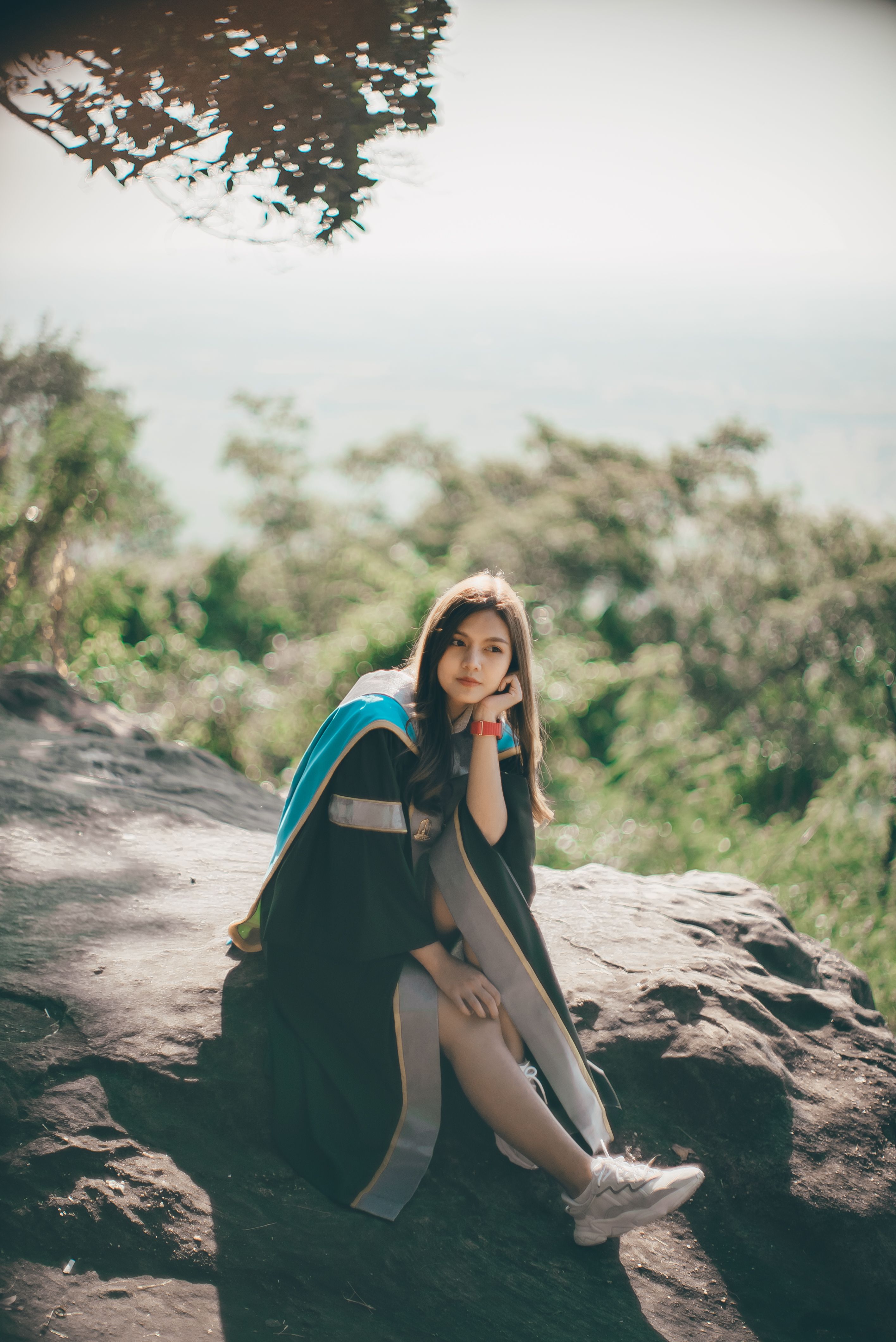 A Woman Wearing a Graduation Gown Sitting on a Rock · Free Stock Photo