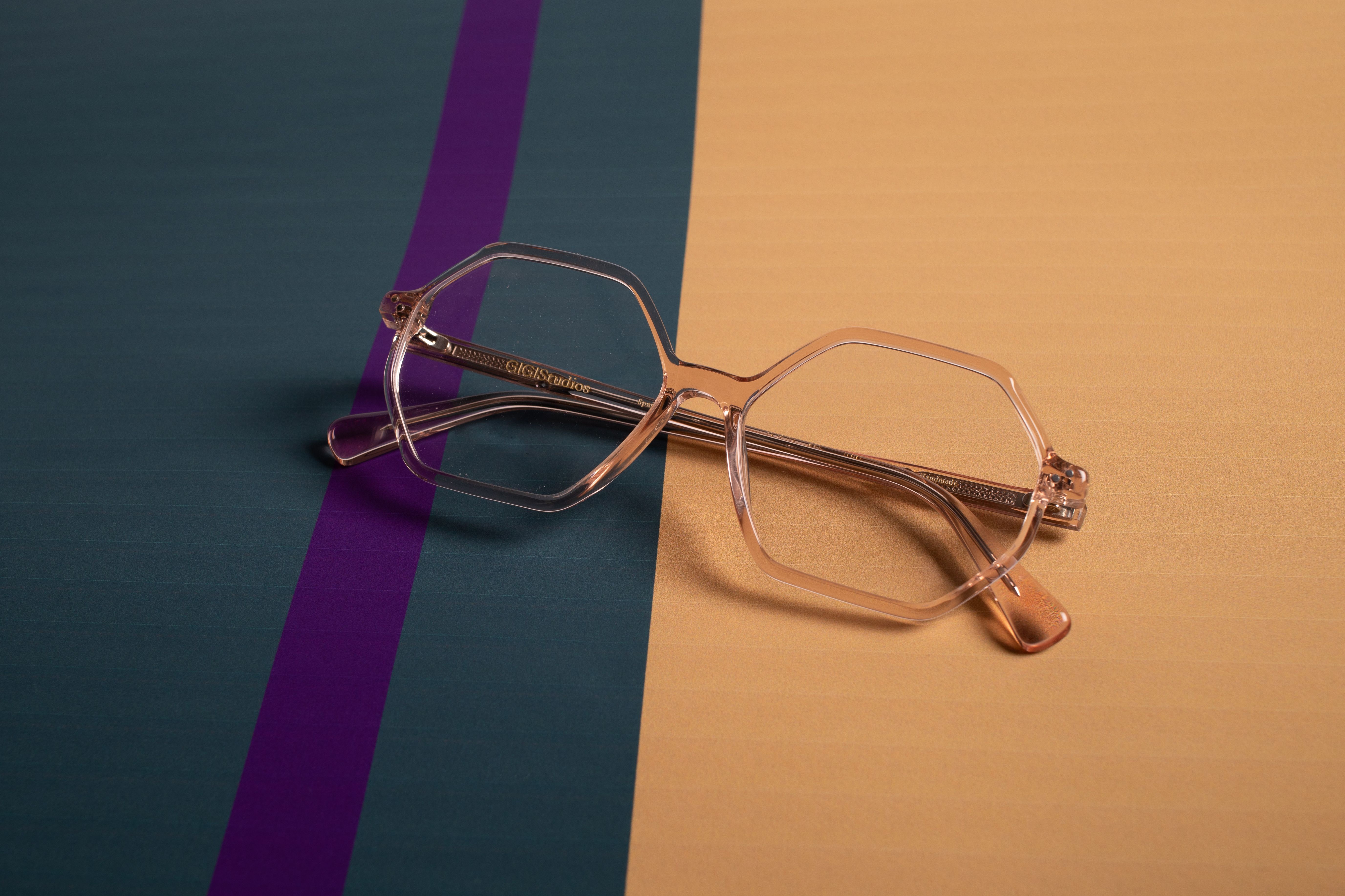 Stylish clear eyeglasses with geometric frames on a modern striped background.