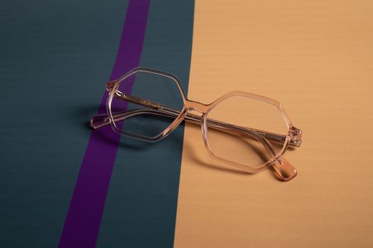 Stylish clear eyeglasses with geometric frames on a modern striped background.