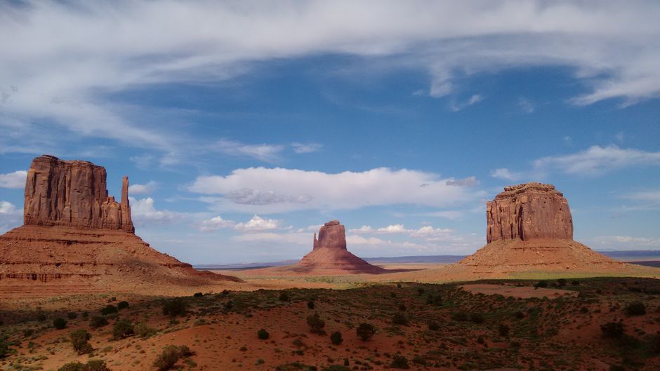 Breathtaking landscape of Monument Valley showing iconic sandstone rock formations against a blue sky.