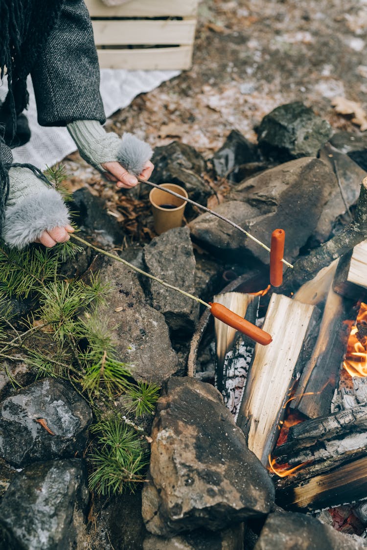 Person Holding A Long Sticks With Sausages