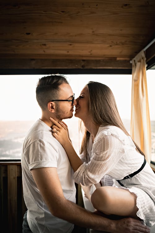 Free Positive young loving couple smiling and hugging while resting in wooden house during romantic weekend Stock Photo