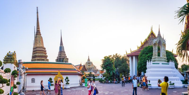 Vibrant view of tourists exploring Wat Phra Chetuphon, a majestic temple in Bangkok, Thailand.