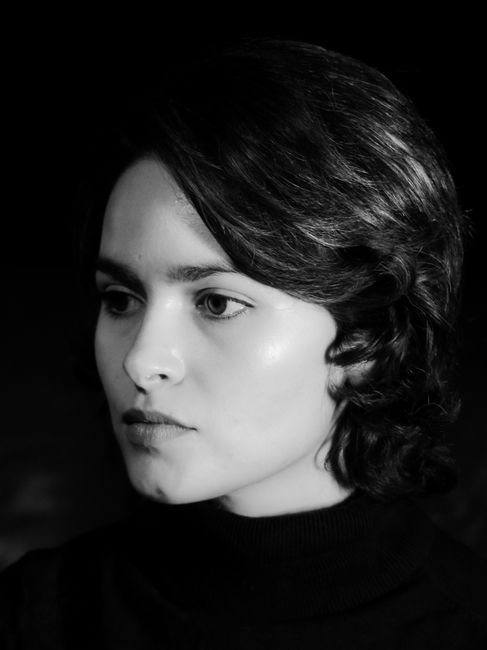A striking black and white studio portrait of a woman with short hair, exuding elegance and confidence.