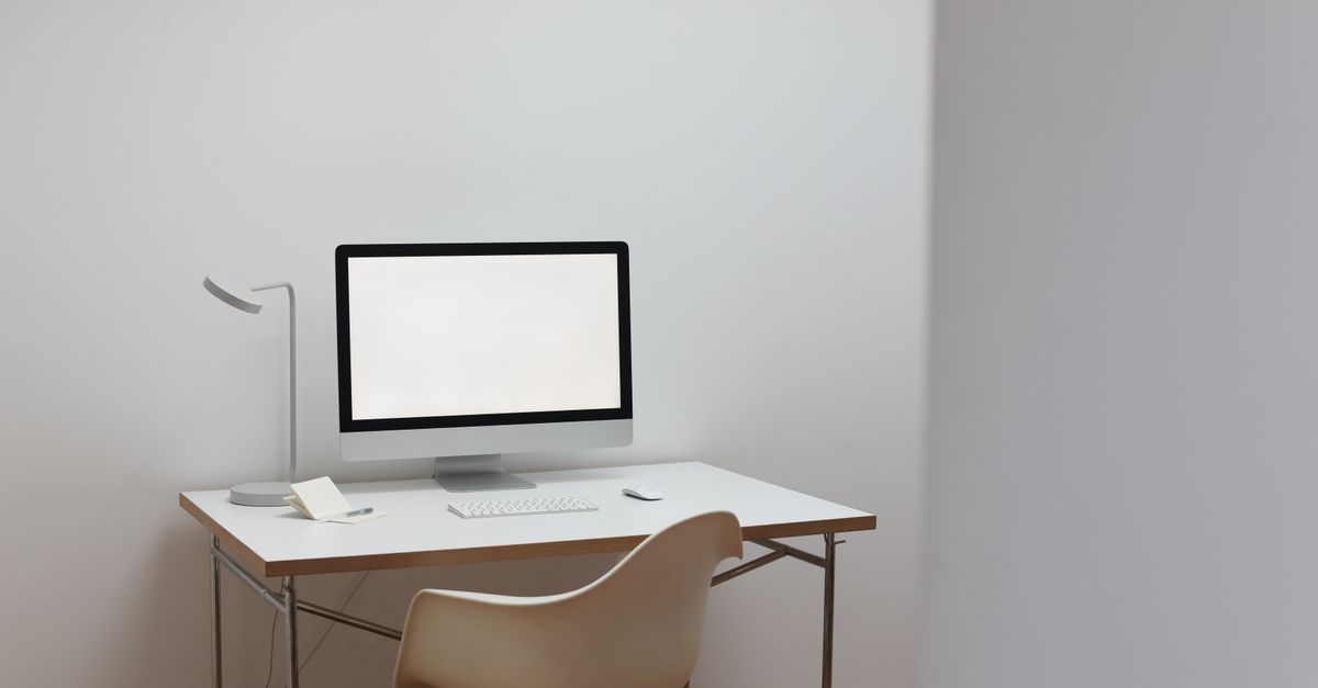 A modern, minimalist home office with a blank screen computer on a tidy desk, emphasizing simplicity and style.