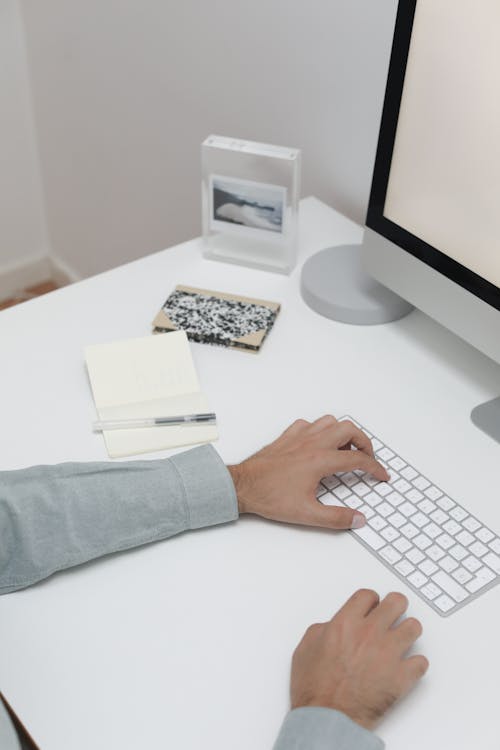 Personne En Chemise à Manches Longues Bleue à L'aide D'un Clavier D'ordinateur Blanc