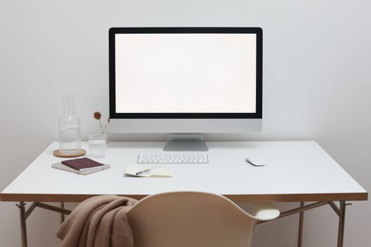 Interior of modern office with wireless mouse and keyboard under monitor on table near chair