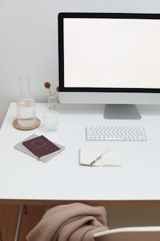 Creative workspace with personal computer and glass bottle with water near paper notebooks