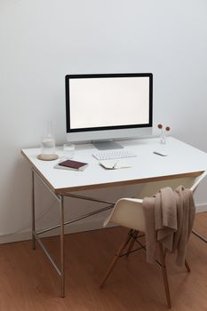 Interior of contemporary room in simple style with computer near bottle and glass with water