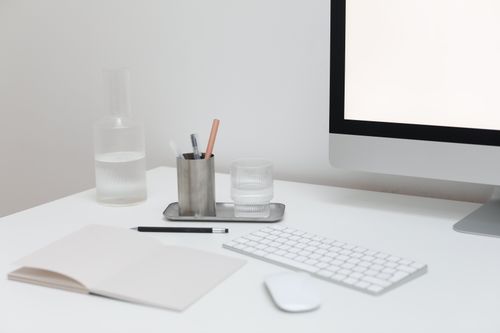 Free Modern computer with wireless keyboard and mouse on table with open notepad and bottle of water Stock Photo