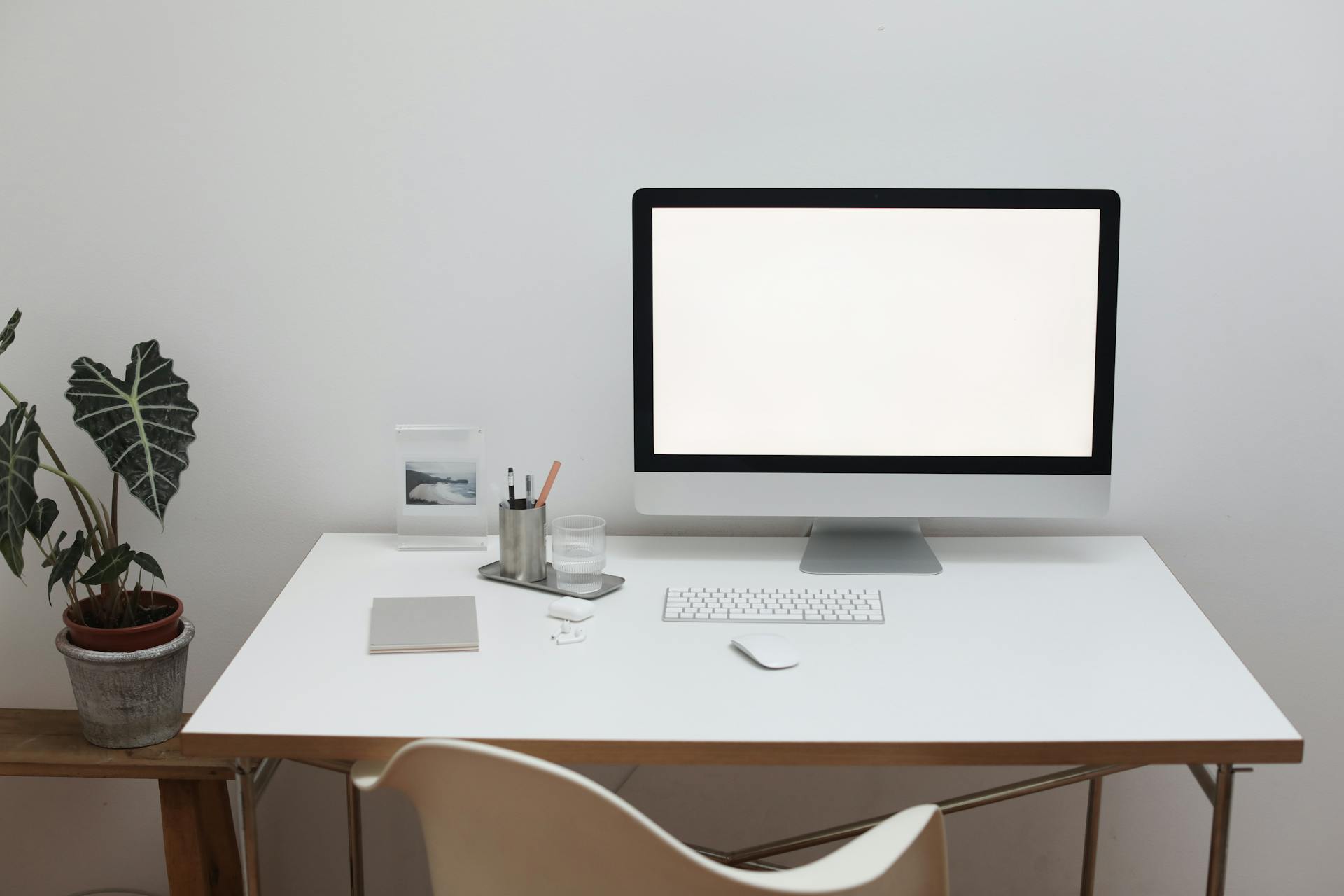 Modern computer with large screen and wireless keyboard near mouse on table in room