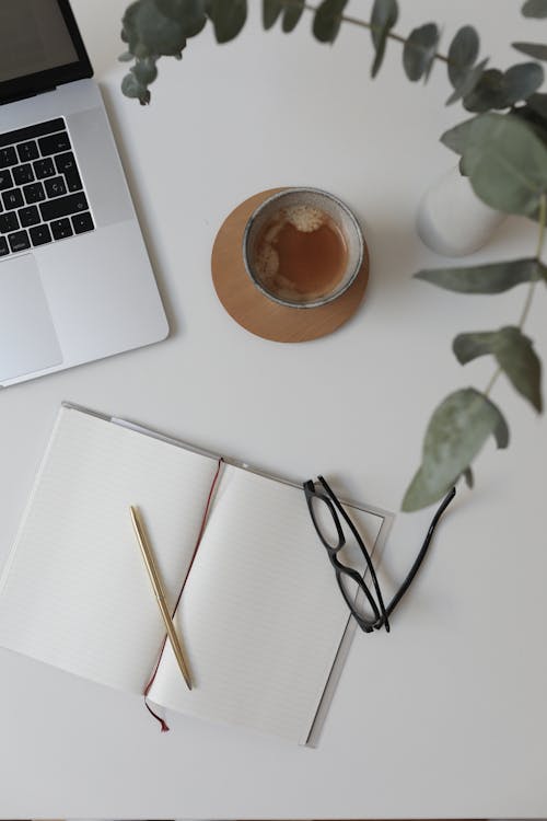 Free Top view of notebook under pencil and glasses near cup of coffee and netbook Stock Photo