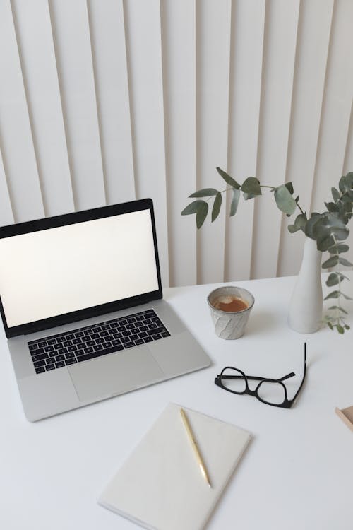 Macbook Pro à Côté De La Tasse En Céramique Blanche Sur Table Blanche