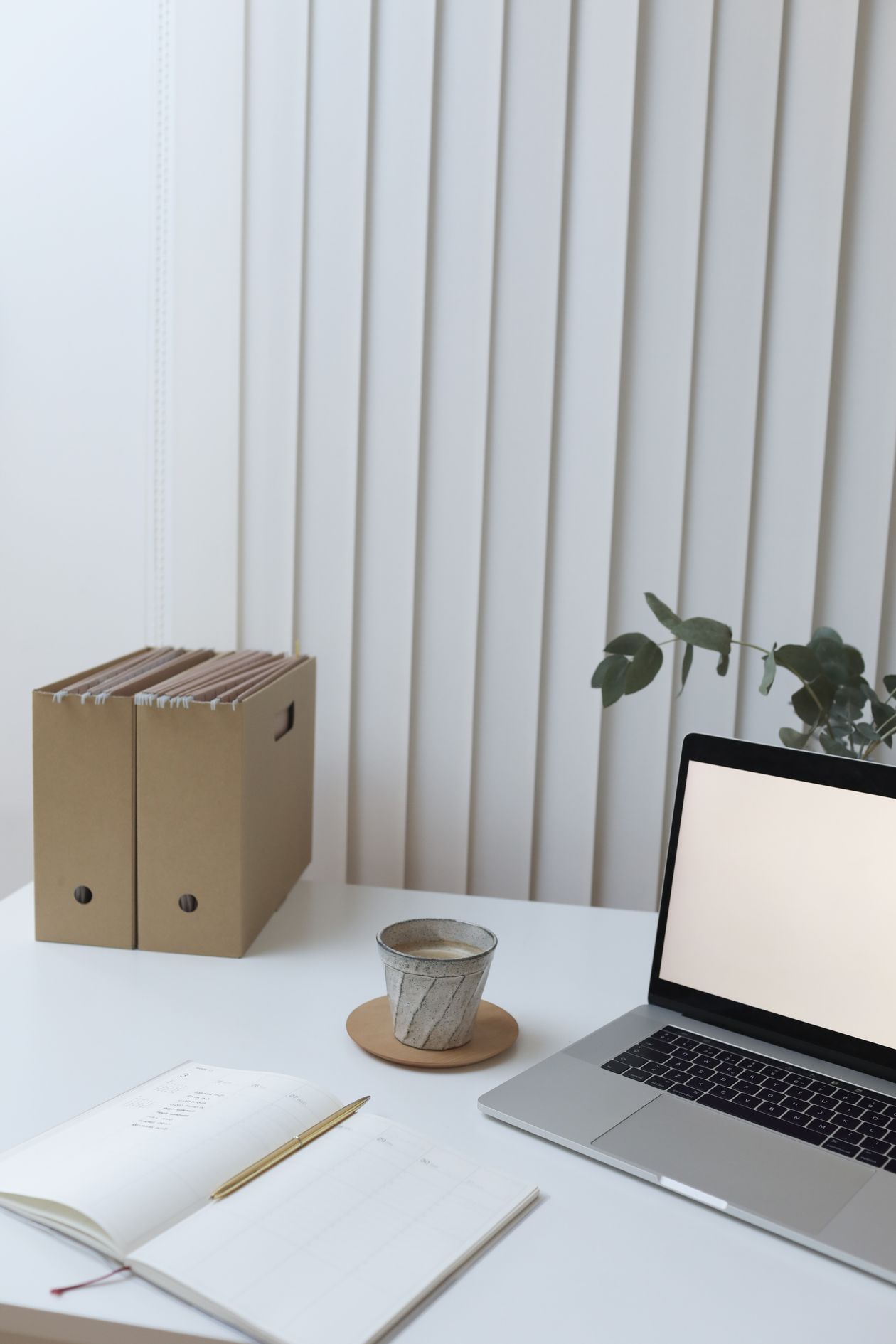 Organised folders, a notebook and a laptop on a desk