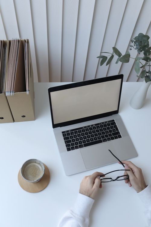 Free From above of crop unrecognizable person sitting at table with coffee and folders while working on netbook in workplace Stock Photo