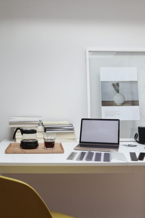 Free Working desk with laptop reversal film tapes and framed photo arranged with coffee glass and pot and books stack Stock Photo