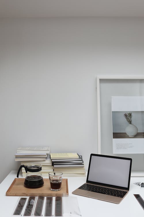 бесплатная Ноутбук на столе рядом со стаканом кофе и стопкой книг Стоковое фото