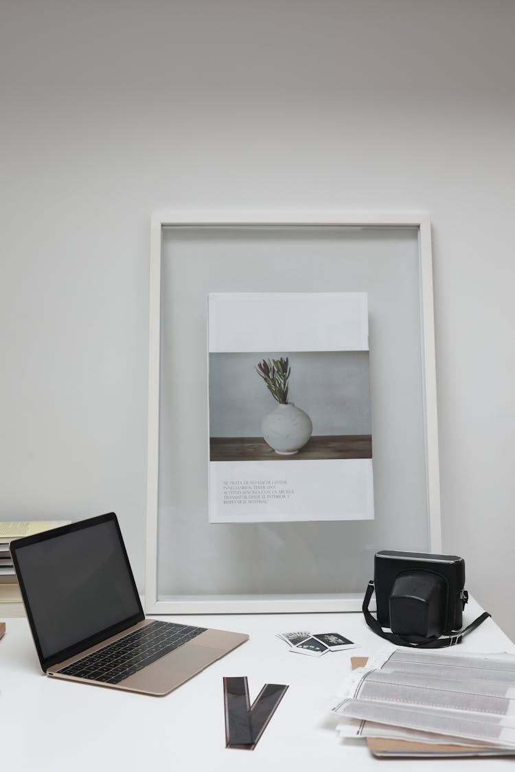 Laptop And Vintage Camera With Negative Films Placed On Desk In Office