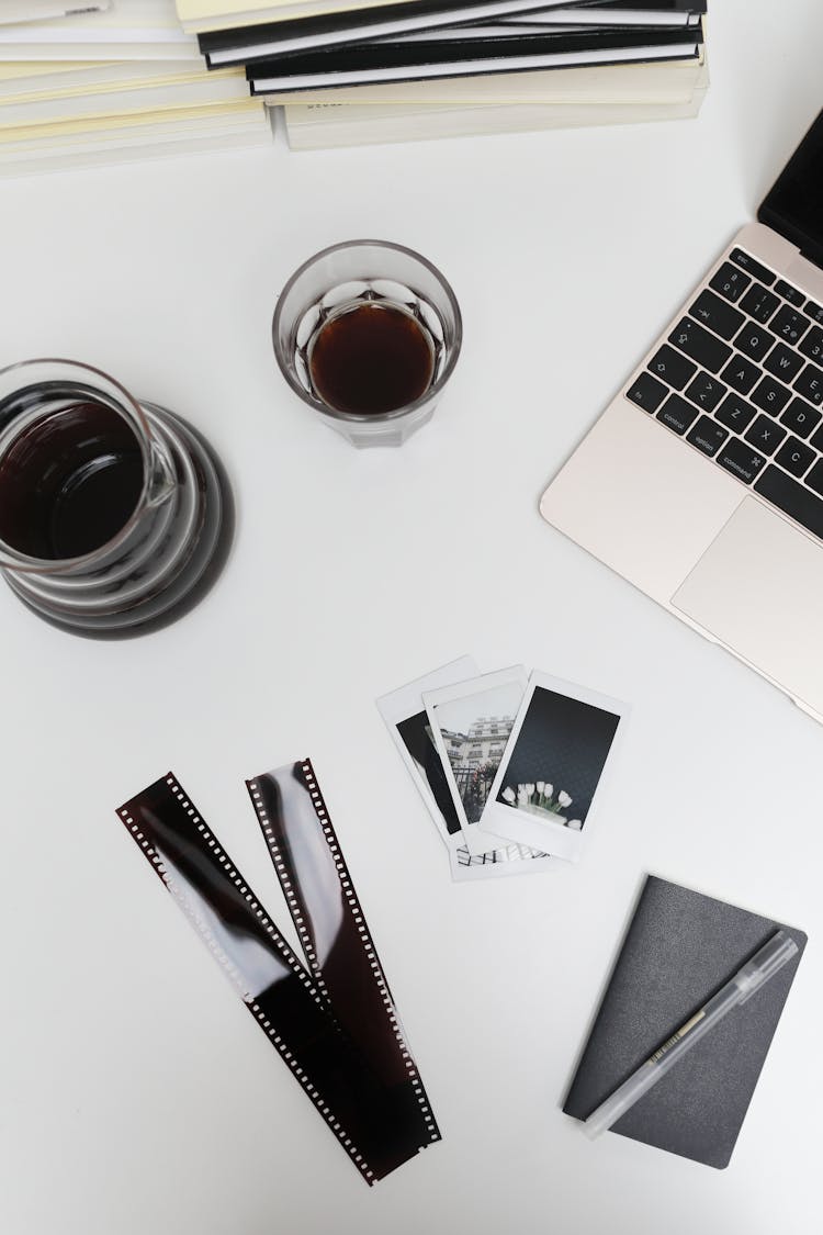 Laptop With Photographic Films And Instant Photos Placed On Desk Near Coffee Glass