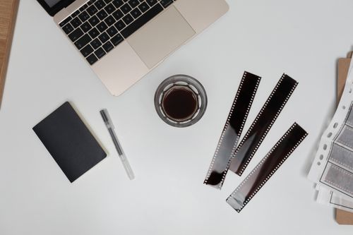 Free Top view of filmstrips with coffee cup and notebook placed on working desk with opened laptop Stock Photo