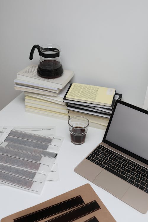 бесплатная Macbook Pro рядом с прозрачной стеклянной кружкой на белом столе Стоковое фото