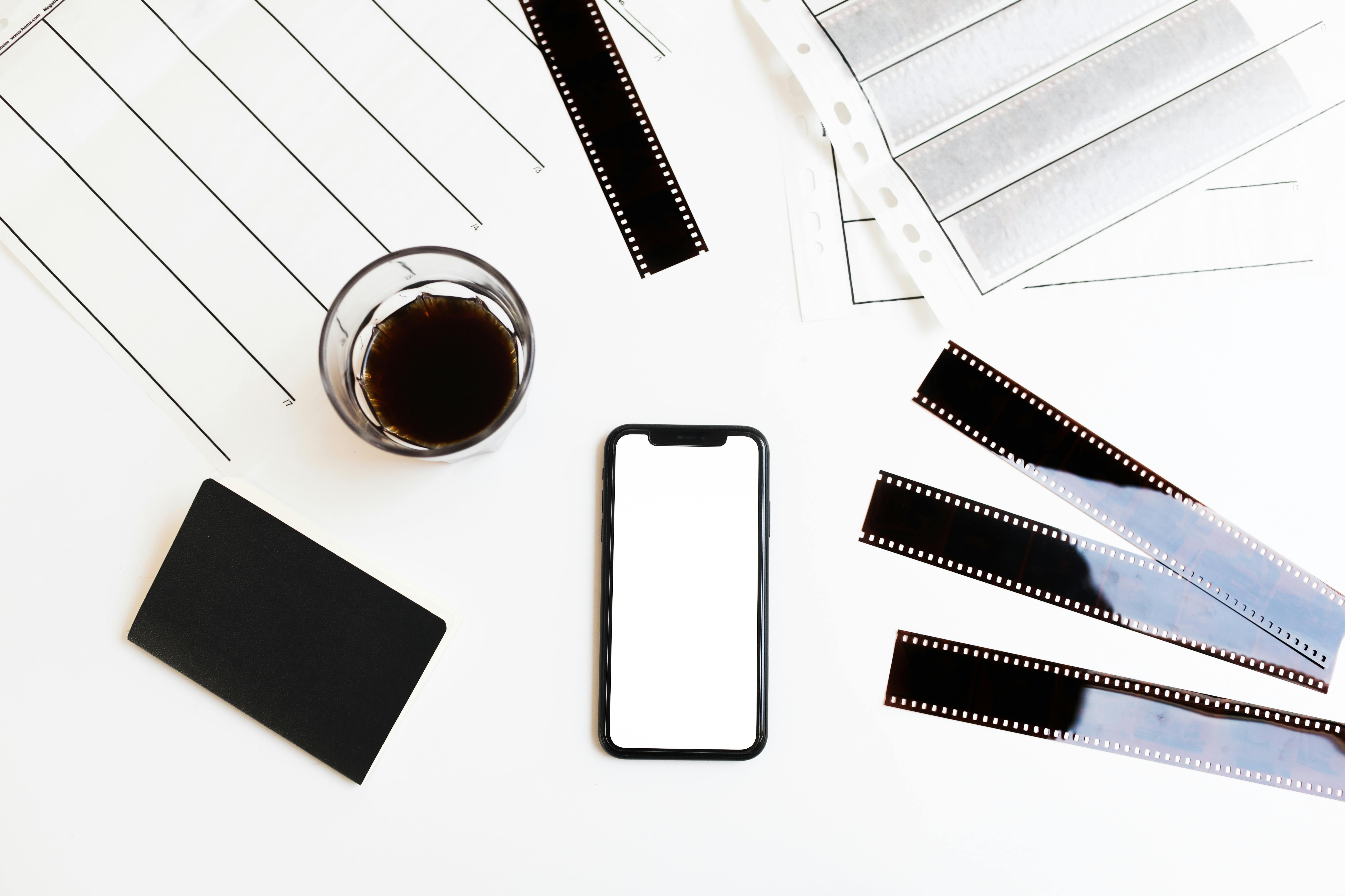 smartphone and filmstrips arranged on table with coffee and notebook