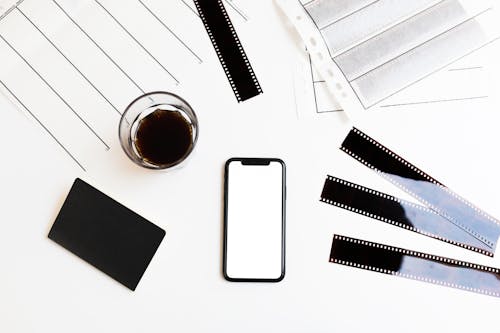 Free Smartphone and filmstrips arranged on table with coffee and notebook Stock Photo