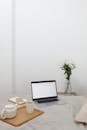 Tea set and laptop placed on bed near table with bunch of flowers
