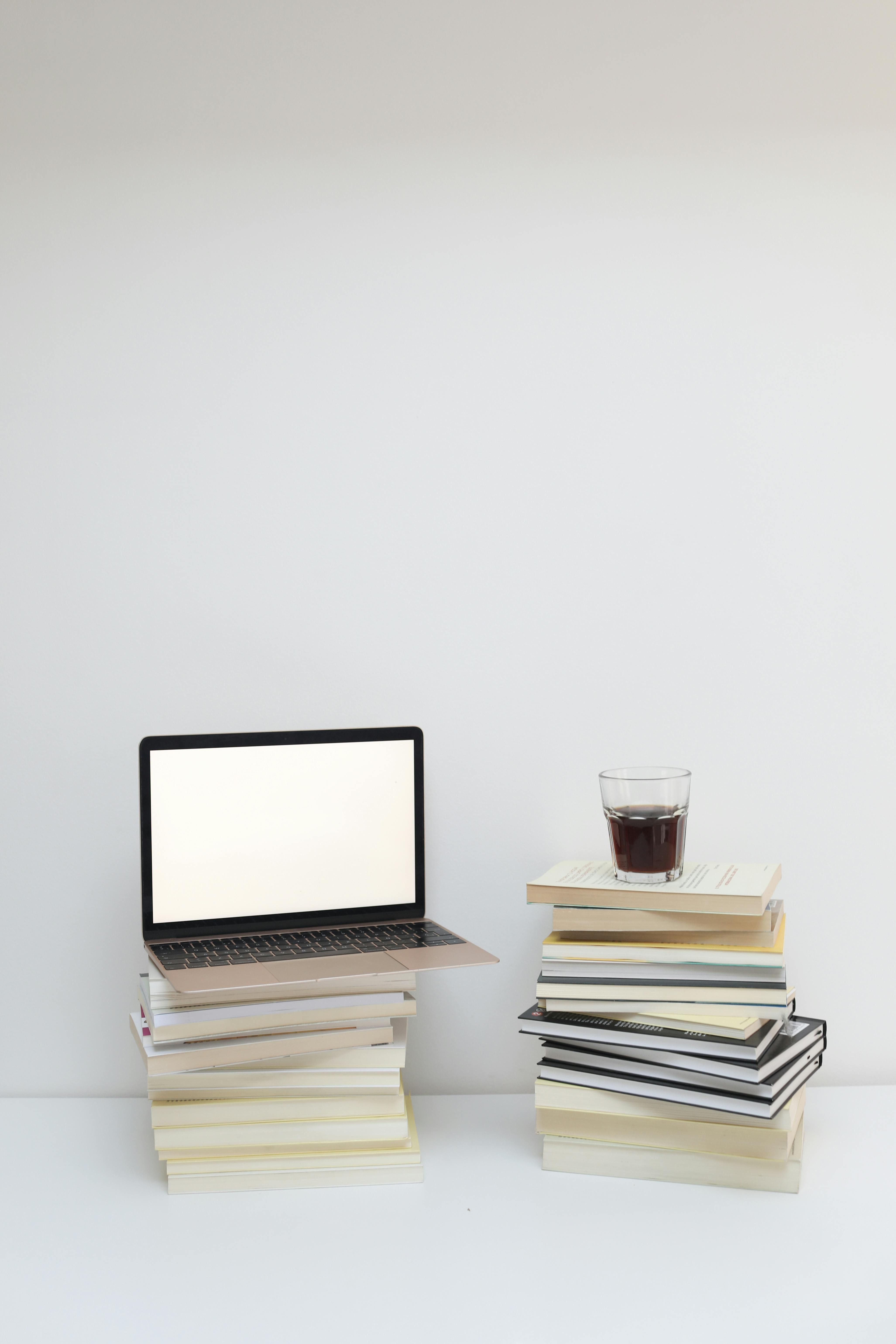 a laptop and glass of coffee placed on top of stack of books