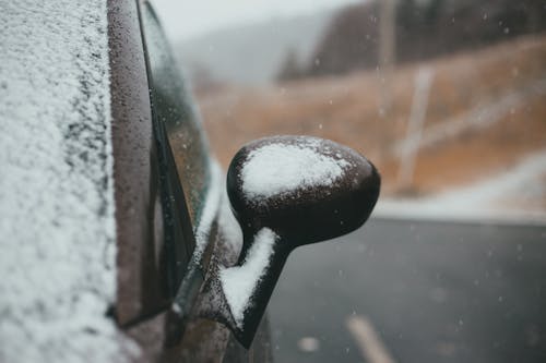 Car driving on asphalt road during snowfall