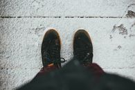 From above of crop anonymous person in warm outerwear standing on snowy wooden boardwalk