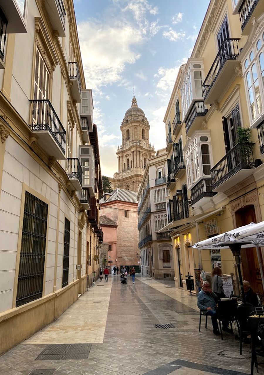 Narrow street in Malaga old town with the cathedral tower behind it