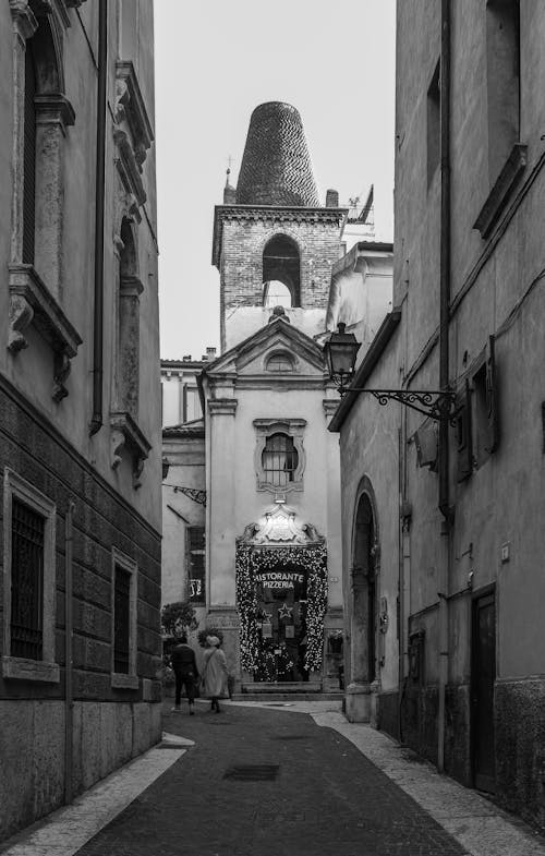 Grayscale Photo of People Walking on the Narrow Street