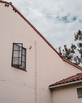 Sunny day view of modern house exterior with open window and red tiled roof.
