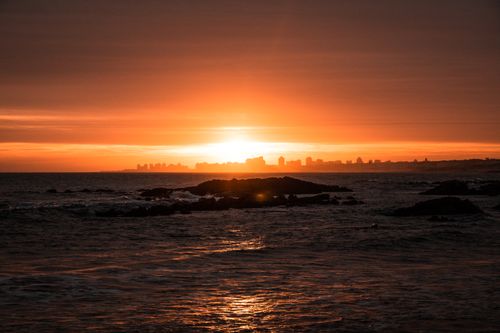 Free Breathtaking view of Punta del Este skyline silhouetted against a vibrant sunset over the ocean horizon. Stock Photo