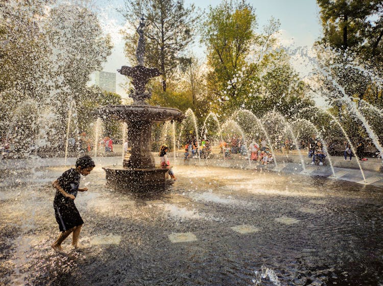 Kids Playing On The Water Fountain