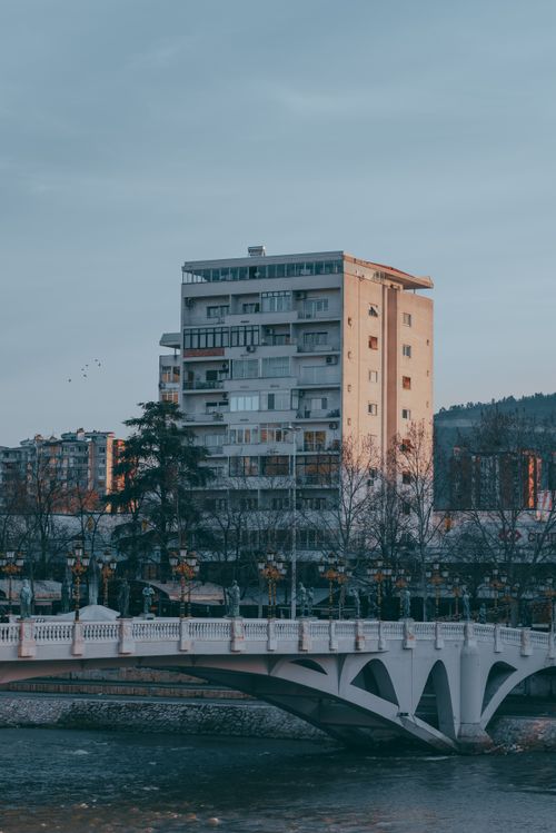 Free A scenic view of a bridge over a river with city buildings in Skopje, North Macedonia. Stock Photo