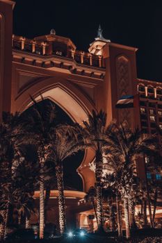 Nighttime shot of the iconic Atlantis Hotel entrance and palm trees in Dubai.