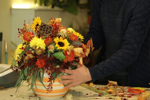 Person Holding a Round Vase with Assorted Flowers