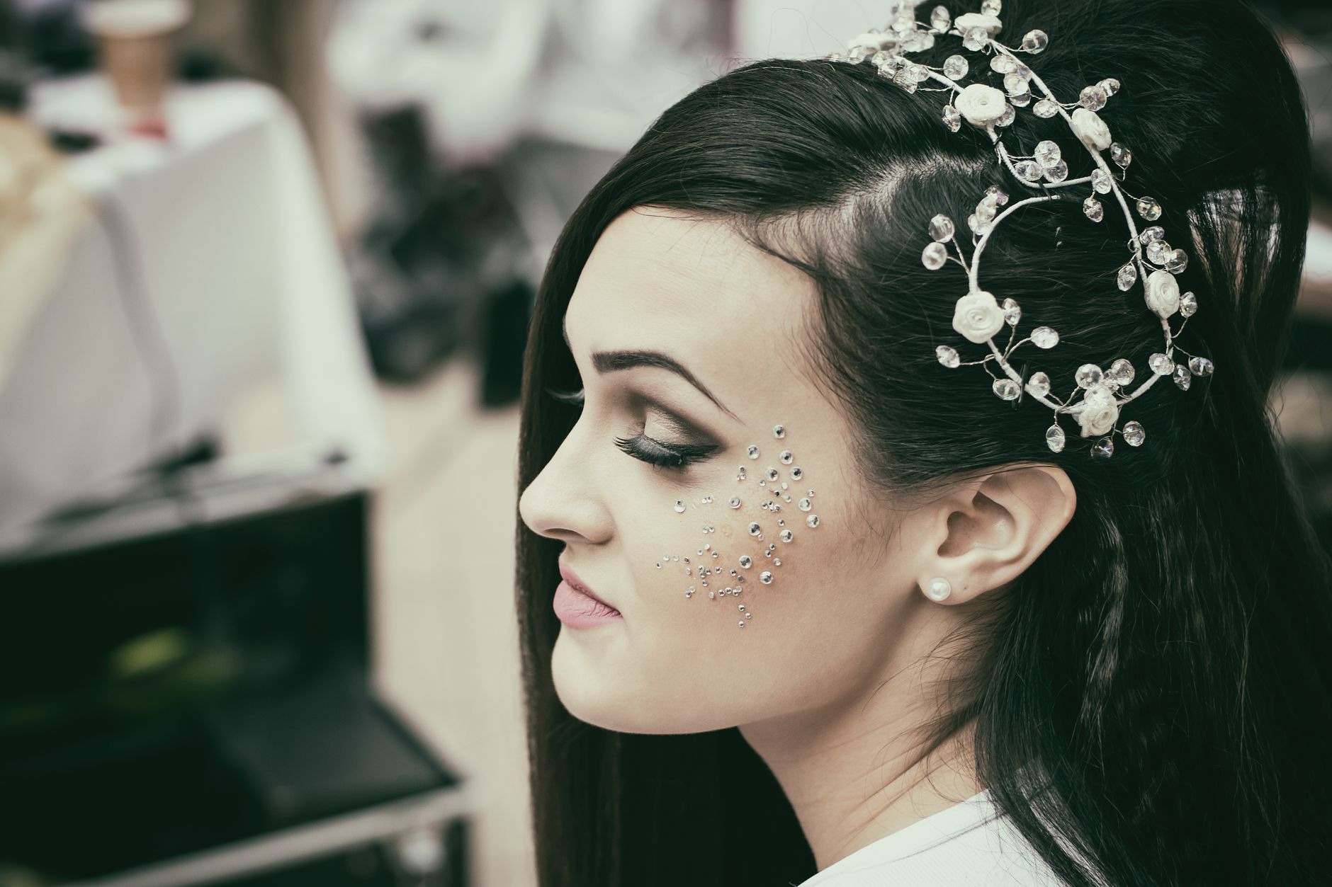 Close-up of a bride showcasing elegant makeup and a detailed hairpiece with floral designs.