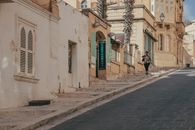 A woman walking along a picturesque street in Victoria, Gozo, Malta under a warm sun.