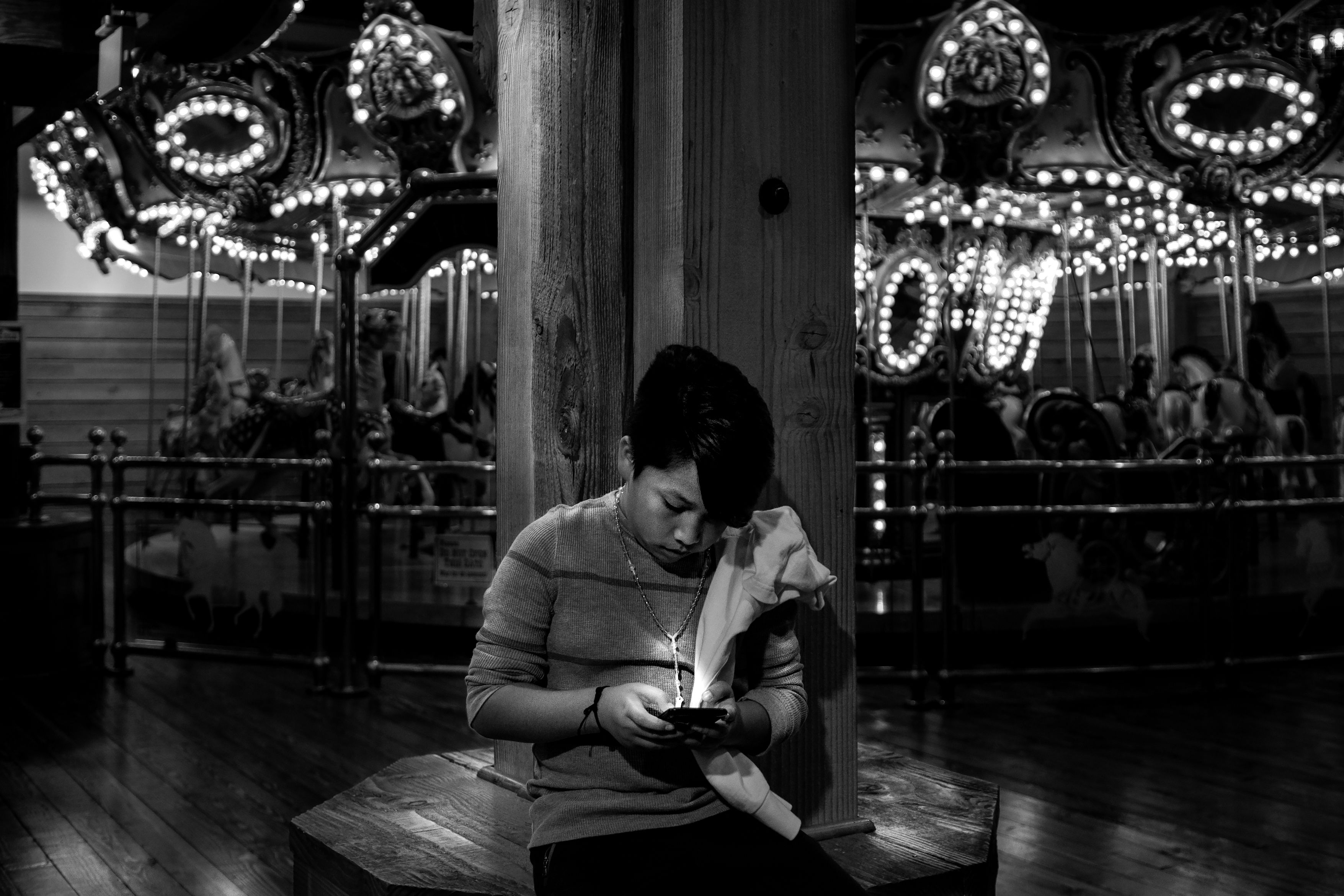 person holding a smartphone in black and white mode, looking at it with a contemplative expression