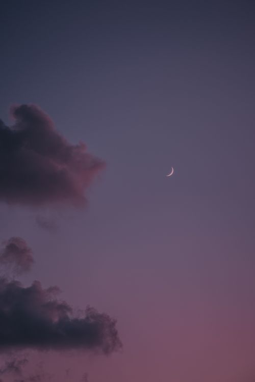 Free A crescent moon peeks through clouds in a moody Malta night sky. Stock Photo