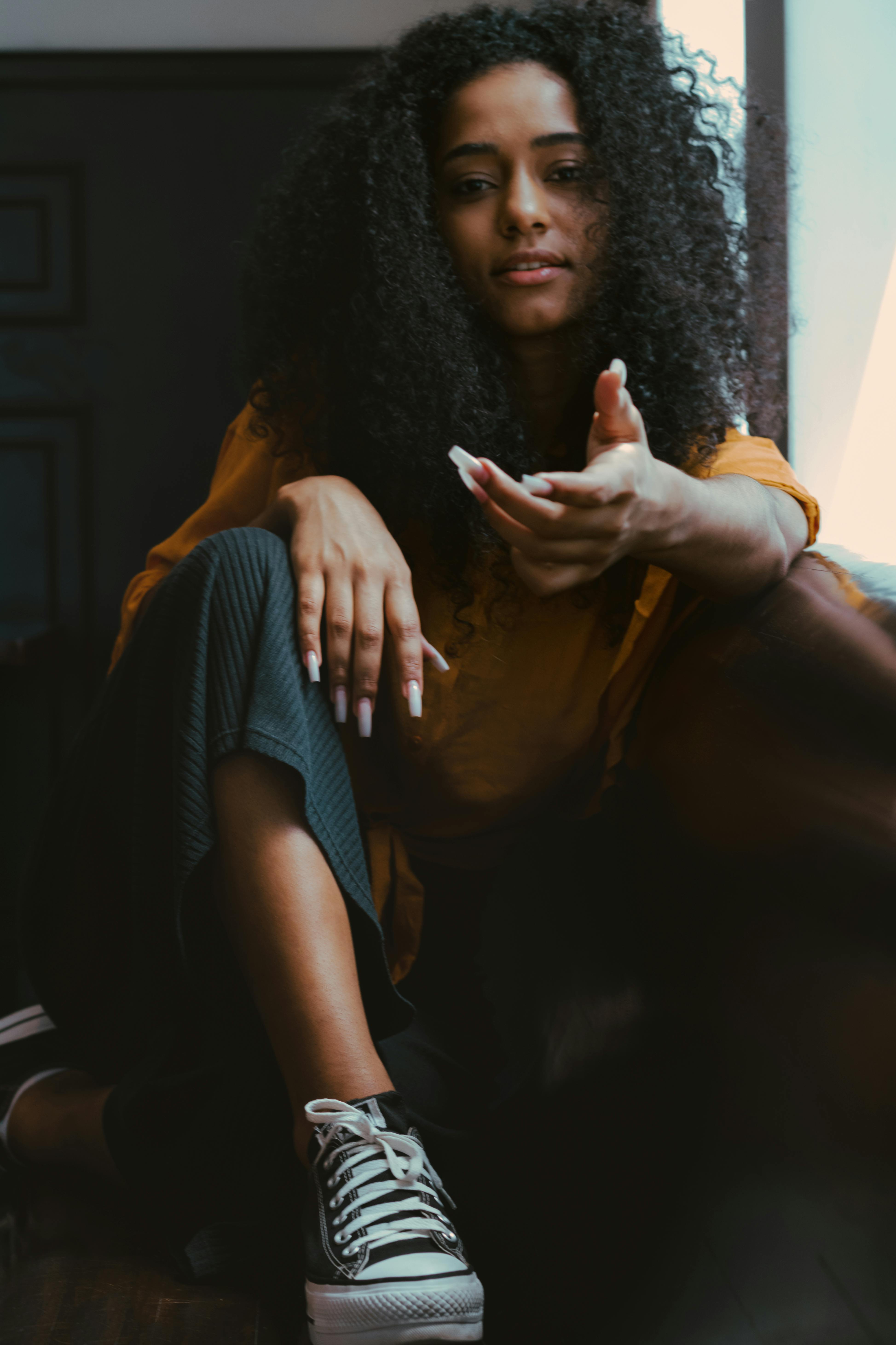 Thoughtful young black woman sitting in green armchair · Free Stock Photo