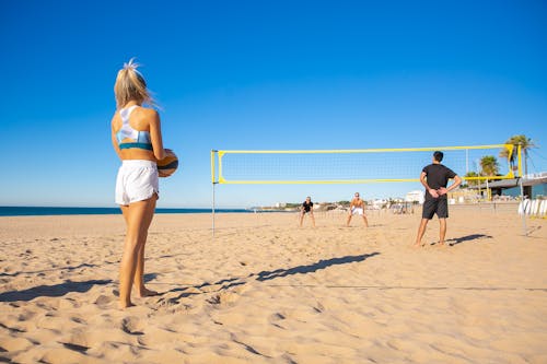 Donna In Pantaloncini Bianchi E Camicia Bianca In Piedi Sulla Spiaggia