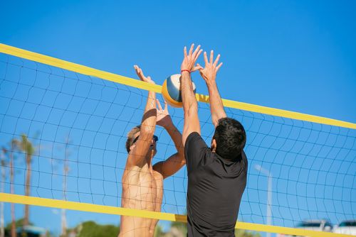 Free Two men playing beach volleyball under a clear blue sky, showcasing athletic skill and competition. Stock Photo