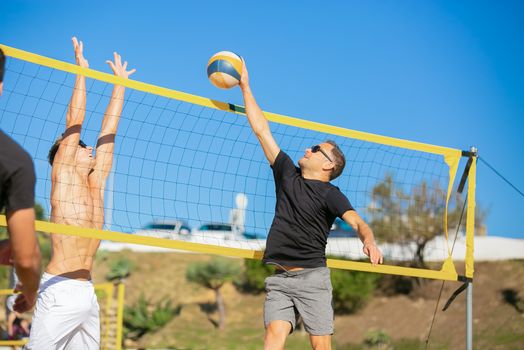 Two men competing in an intense beach volleyball game under the bright blue sky.
