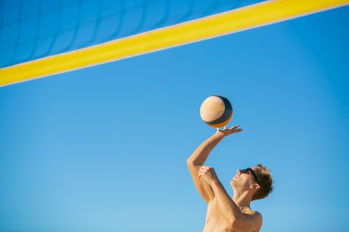 Free A man in sunglasses serves a volleyball outdoors on a sunny day. Stock Photo