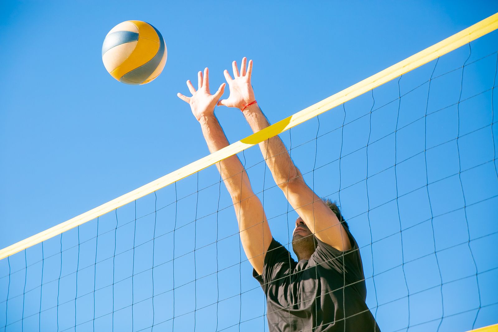 Volleyball player jumping at an indoor court net