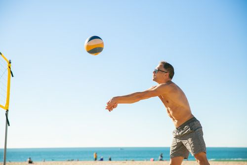 Free Shirtless man playing beach volleyball under a clear blue sky Stock Photo